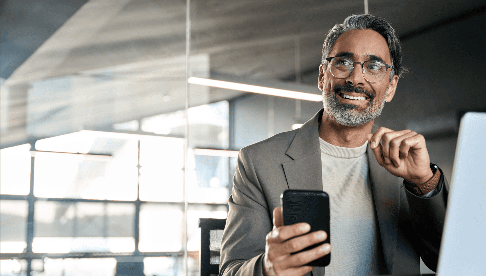 Um homem sorridente falando ao celular e usando o computador