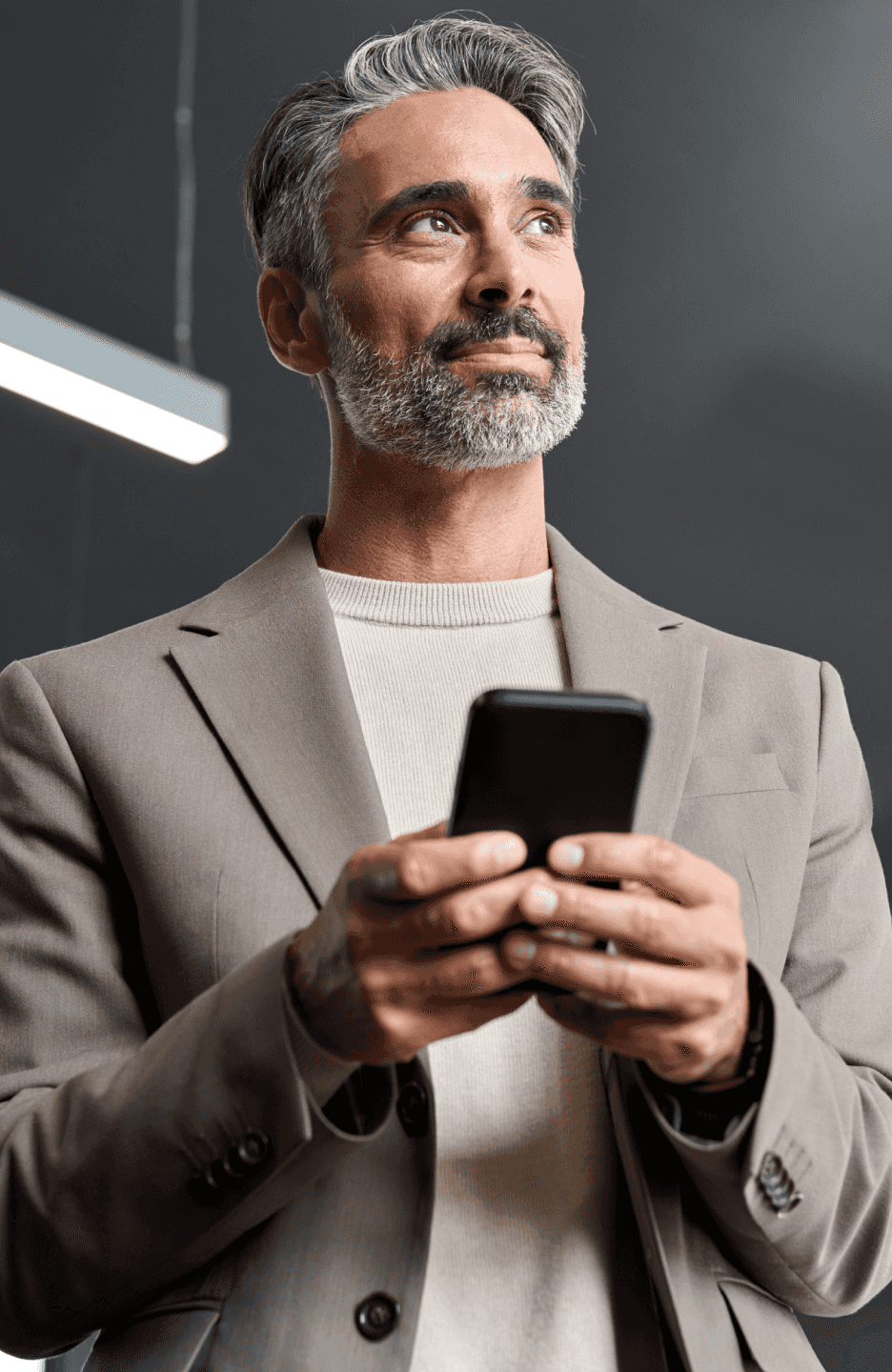 Homem segurando um celular e olhando para o horizonte