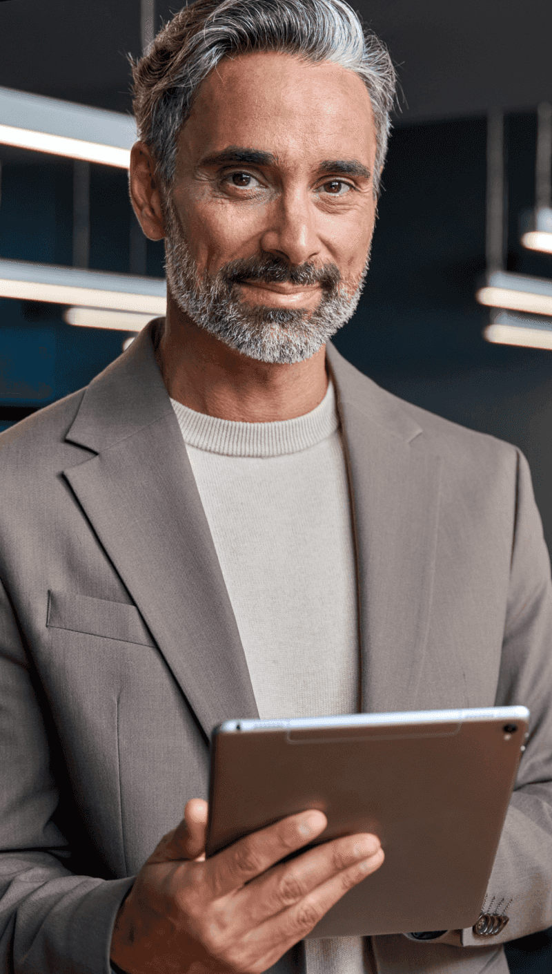 Um homem sorridente falando ao celular e usando o computador