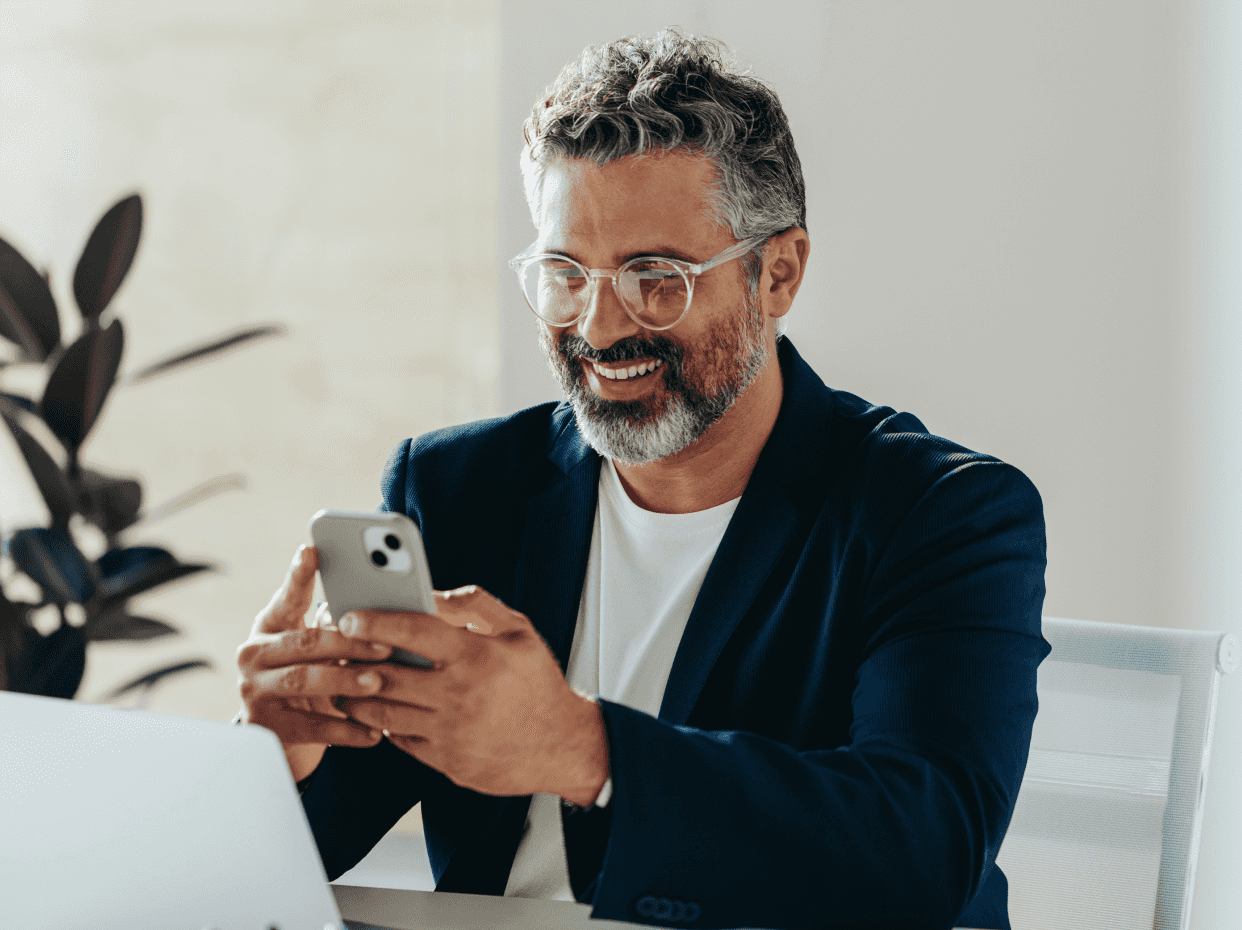 Um homem sorridente mexendo no celular