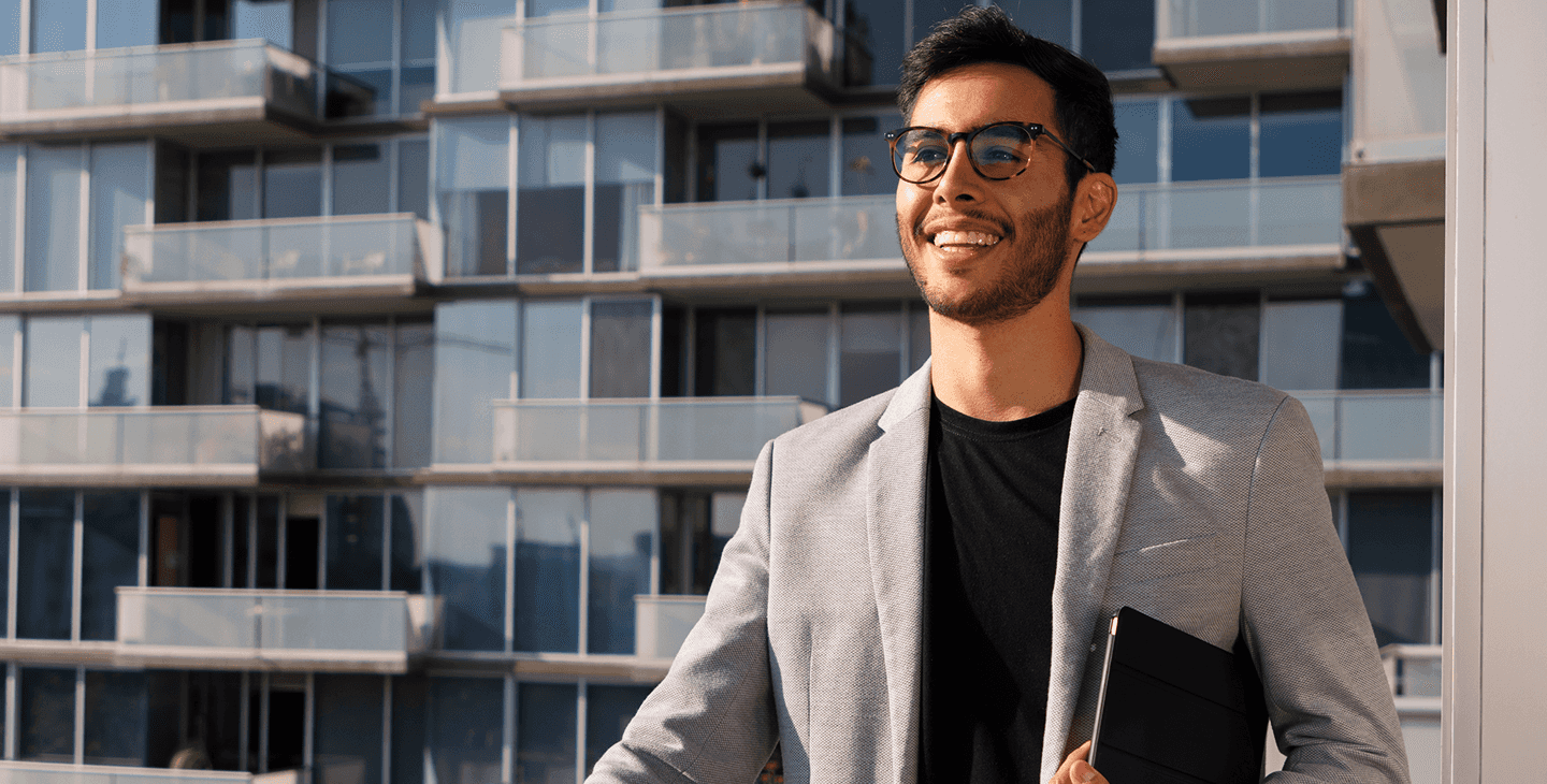 Um homem sorridente falando ao celular e usando o computador