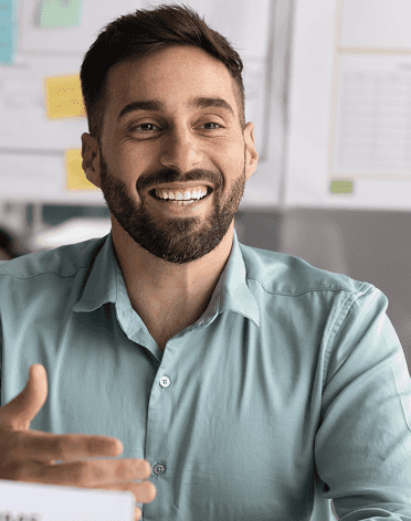 Um homem sorridente falando ao celular e usando o computador